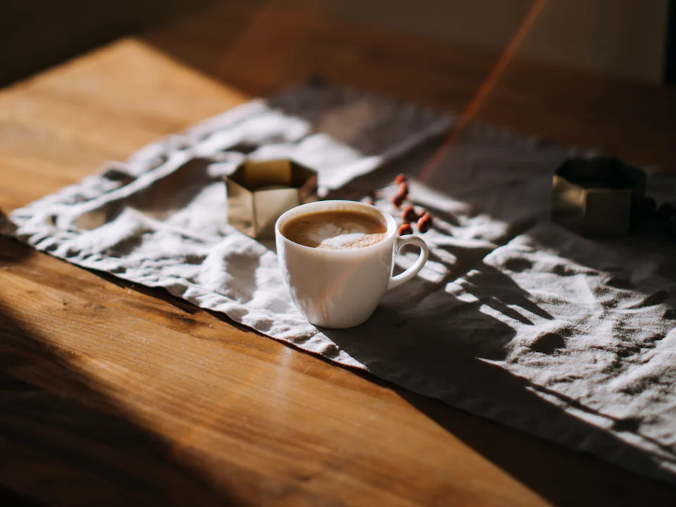 Taza de café sobre una mesa de madera con luz de tarde