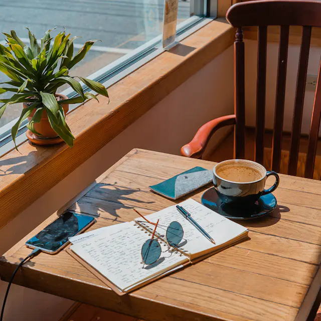 Rincón de trabajo junto a una ventana con una taza de café y una planta